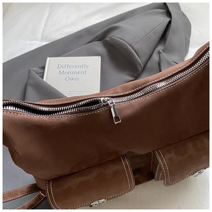 Detail view of brown faux leather shoulder bag with white contrast stitching and silver zipper