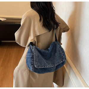 Dettaglio di una borsa a tracolla in denim blu vintage indossata su un cappotto beige chic