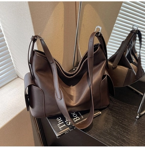 Detail view of large dark brown PU leather tote bag with soft folds and side flap pocket