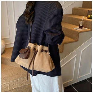 Detail view of large khaki suede bucket bag with drawstring and mini pouch attachment