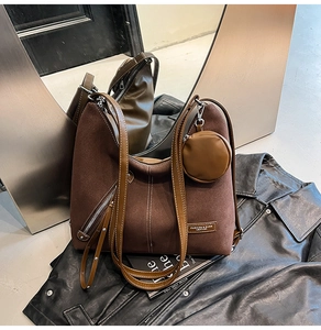 Detail of brown faux suede tote with leather patch, white stitching and mini pouch