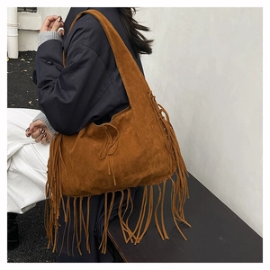 Detail of bohemian suede tote bag with long fringes in caramel brown and wide strap