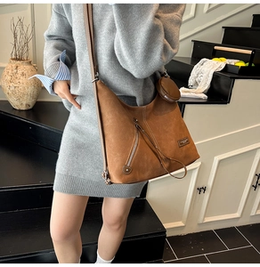 Detail view of brown suede tote bag with zip pocket and round coin purse attachment