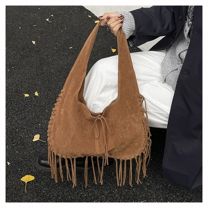 Detail view of brown faux suede hobo bag with long tassels and woven edge accents