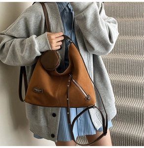 Detail view of caramel brown suede tote bag featuring small round pouch and side tassel zipper