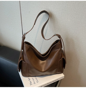 Detail of a brown PU leather hobo bag with side flap pocket and silver hardware