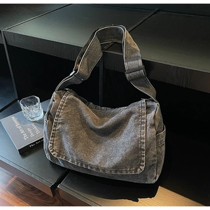 Dettaglio laterale di borsa a tracolla in denim grigio lavato con ampia tracolla regolabile