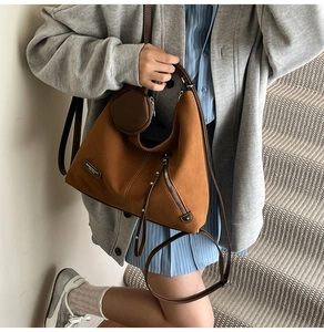Brown suede hobo bag with zip detail and small round pouch shown on stone steps
