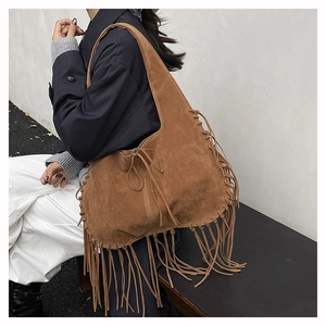 Close-up of bohemian brown suede tote bag with long fringe tassels and woven edge detail