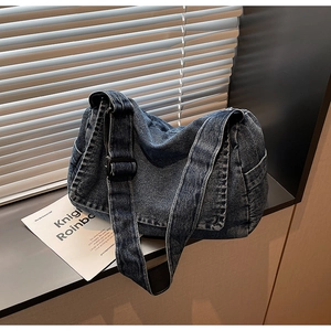 Dettaglio della borsa a tracolla in denim lavato blu scuro con ampia cinghia regolabile