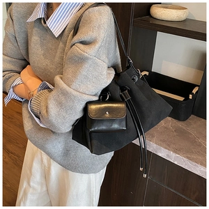 Dettaglio borsa a secchiello nera con coulisse e pochette in pelle decorativa sulla modella