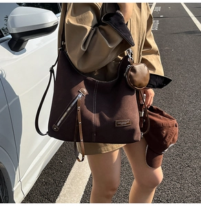 Detail of dark brown hobo bag featuring contrast stitching and external zipper pocket