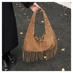 Close-up of brown suede hobo bag with tassel details and woven accents in autumn setting