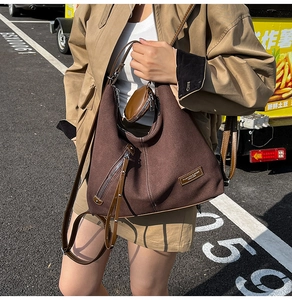 Detail of a large brown canvas hobo bag with a leather strap and small detachable coin pouch