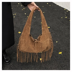 Close-up of handmade suede tote bag featuring bohemian tassels and braided side details