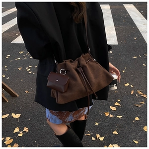 Macro shot of dark brown suede drawstring bucket bag with a matching mini coin purse charm