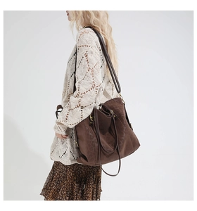 Detail view of large brown faux leather tote bag with vintage gold metal zippers and strap