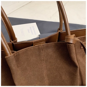 Vue macro du cabas en daim marron montrant les coutures et la texture du cuir premium