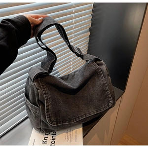 Dettaglio della borsa messenger in denim lavato con tracolla regolabile e tasca laterale grigio