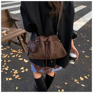 Outdoor shot of dark brown suede drawstring bucket bag with small matching pouch