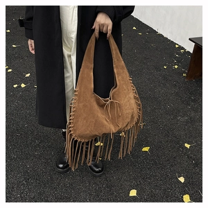 Detail of bohemian suede tote bag with fringe tassels and woven edges in camel brown