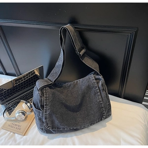 Dettaglio della borsa a tracolla in denim lavato con ampia cinghia e tasca laterale