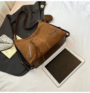 Detail of a brown suede hobo bag with decorative zipper and detachable round pouch charm