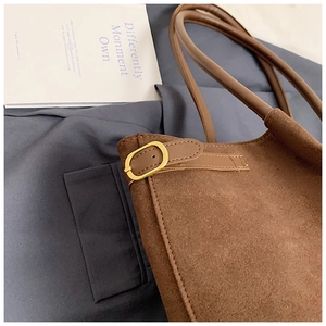 Détail du sac cabas en daim marron foncé avec boucle en métal doré et bandoulière en cuir