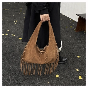 Detail of bohemian suede tote bag with fringe tassels and woven side lacing accents
