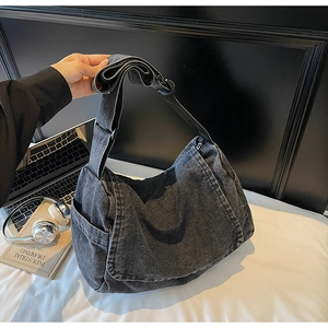 Dettaglio macro del denim grigio scuro lavato e tracolla regolabile della borsa retrò