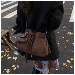Close-up of a vintage dark brown suede tote bag with drawstring closure and small pouch