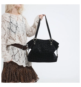 Detail of black leopard embossed tote bag with gold metal rings and stylish shoulder straps