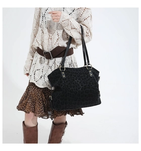 Detail of large leopard print tote bag featuring black leather handles and gold metal rings