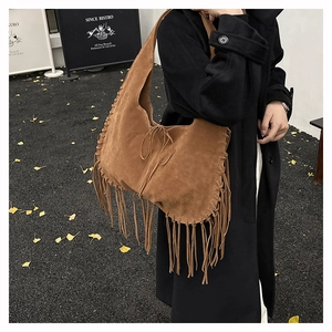Close-up of brown suede tote bag featuring long fringes and bohemian braided details