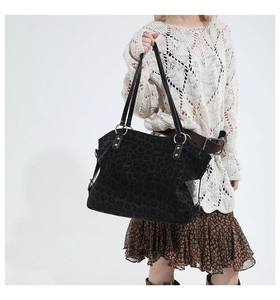 Macro detail of black tote bag featuring matte leopard texture and golden ring hardware
