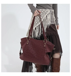 Detail of burgundy leopard print tote bag with gold hardware on model shoulder