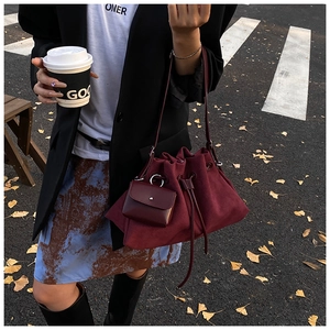 Detail view of burgundy drawstring bucket bag with matching mini purse charm on the side