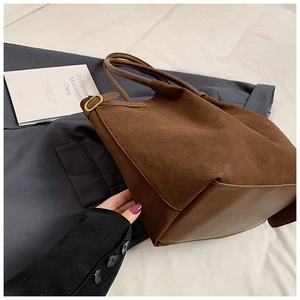 Détail du grand sac cabas en daim marron avec base en cuir et boucles dorées