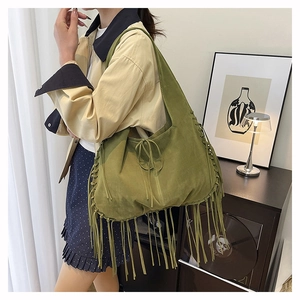 Detail of moss green suede tote bag showing hand-woven knots and long fringe tassels