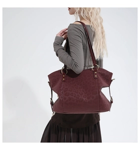 Close-up of wine red leopard print tote bag with gold metal rings and rivet details
