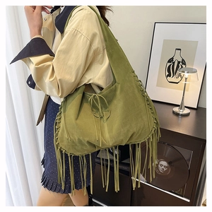 Detail of olive green suede hobo bag with long fringes and boho braided stitching details