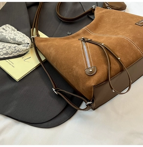 Detail of caramel suede shoulder bag with contrast stitching and metallic branding
