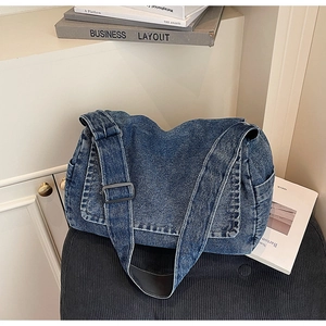 Dettaglio della borsa in denim lavato blu con tracolla larga e fibbia in metallo