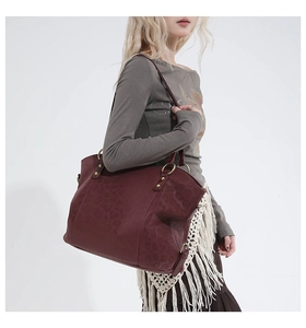 Close-up of dark burgundy tote bag featuring animal pattern texture and tassel details