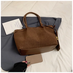Détail du sac cabas marron foncé montrant la base en cuir lisse et la boucle en métal