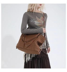Detail view of the brown leather tote bag showing adjustable strap and vintage gold buckle