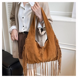 Detailed close-up of brown suede hobo bag featuring long bohemian fringe accents