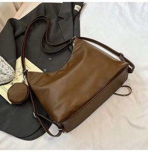 Detail view of brown leather tote bag showing white contrast stitching and a small coin purse