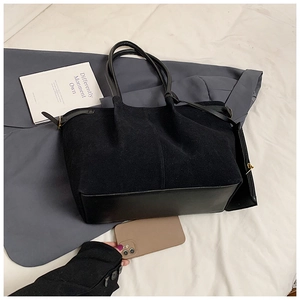 Détail du sac cabas en daim noir avec base en cuir et boucles métalliques réglables