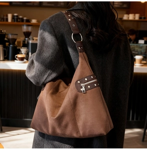 Detailed side view of deep brown suede tote with metal rivets and wide shoulder strap